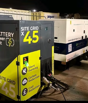 a yellow and black generator that's plugged in, and says 'Silent Running', 'Carbon Reduction', and 'Cost Reduction', and a white genertech generator that has a black stripe going along it.