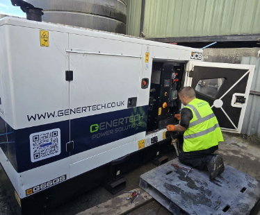 a white genertech generator with a black stripe along the middle getting worked on by a man in a high visibility jacket.