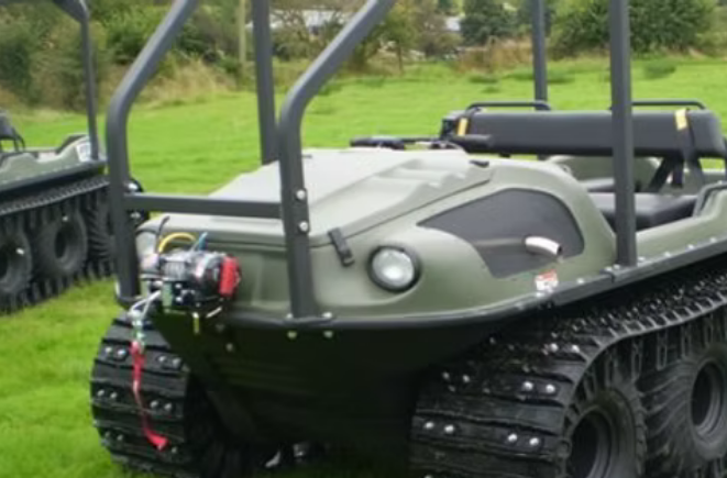 A green buggy that has tracks instead of wheels and has a rope at the front that has a hook attached to it.